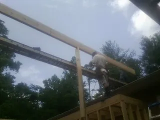 Carpenter setting a ridge beam over a new addition frame — Ice Dam Removal by Roofing Brothers in Weare