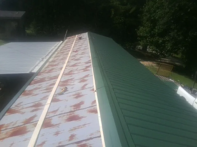 Old rusted panels beside newly installed green metal roofing — Wind Damage Roof Repair by Roofing Brothers in Weare