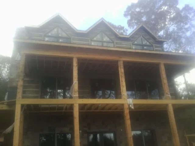 Dormers and porch framing on a large log home under construction — Roof Coating work by our crew in Weare