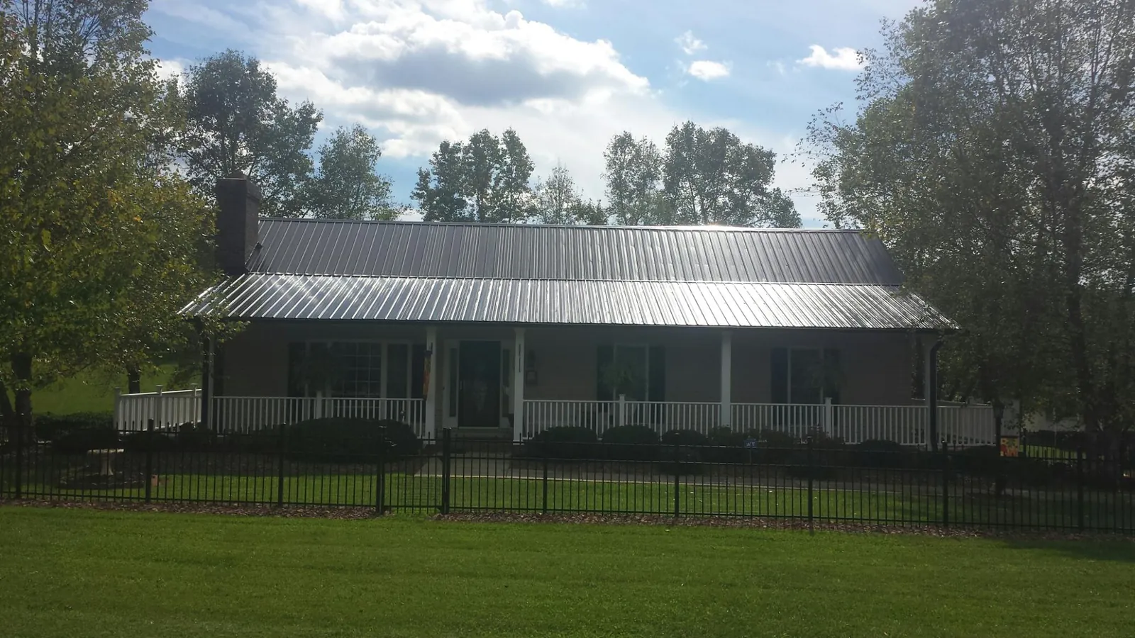 Gray metal roof on a brick ranch with a full width front porch — Gutter Guard Installation work by our crew in Weare