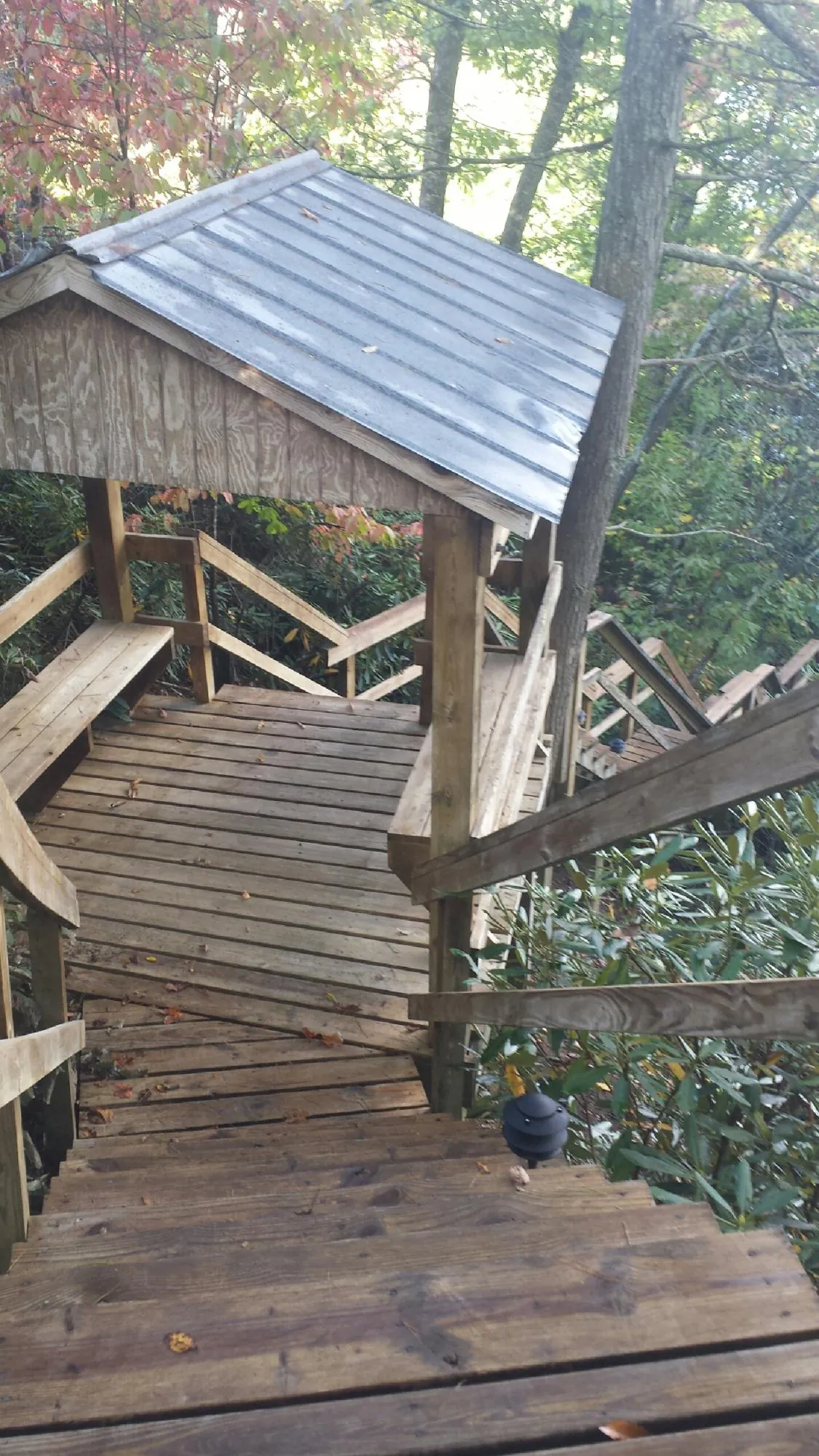 Metal roofed shelter over wooden steps on a wooded walkway — Skylight Repair & Installation work by our crew in Weare